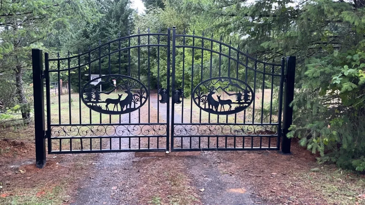 Decorative wrought iron driveway gate with arched design at residential entrance