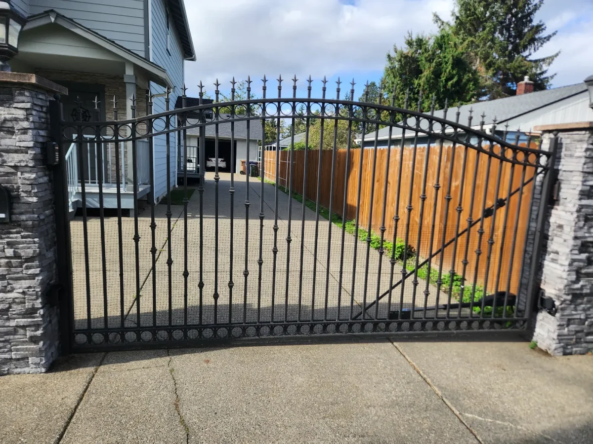 Double swing wrought iron driveway gate installed between stone columns in tampa florida