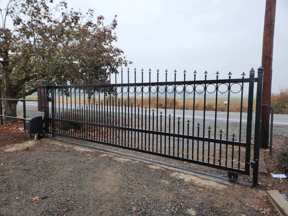 Ornamental metal driveway gate with vertical pickets