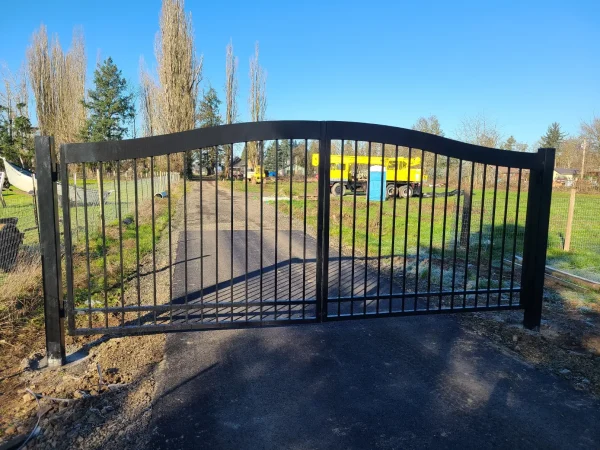Black metal fence gate installed between steel fence panels at residential property