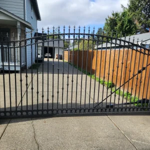 Double swing wrought iron driveway gate installed between stone columns in tampa florida