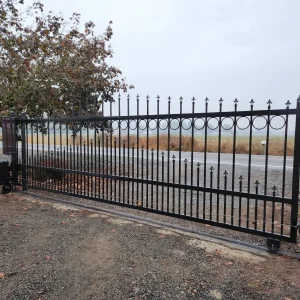 Ornamental metal driveway gate with vertical pickets